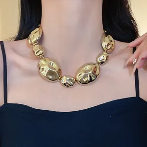 Close-up detail of a chunky gold wrinkled oval link necklace worn by a model.
