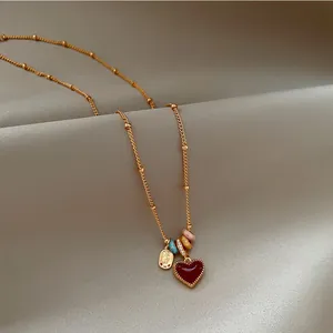 18K gold plated heart pendant necklace with colorful zircon beads on elegant fabric background.
