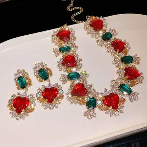 Primo piano di set gioielli vintage con cuori rossi e zirconi verdi su metallo dorato.