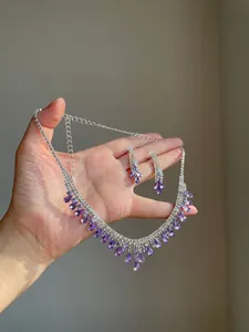 Detailed view of rhinestone teardrop tassel necklace and matching purple earrings