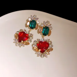 Primo piano di orecchini vintage a cuore con zirconi rossi e verdi incastonati in oro