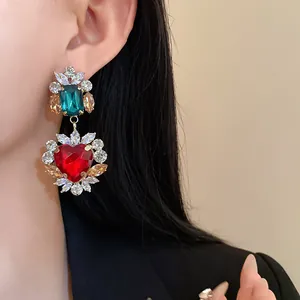 Dettaglio macro di orecchini a cuore vintage di lusso con gemme rosse e verdi brillanti