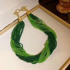 Detailed view of Bohemian multi-layered green seed bead necklace with vintage gold toggle clasp.