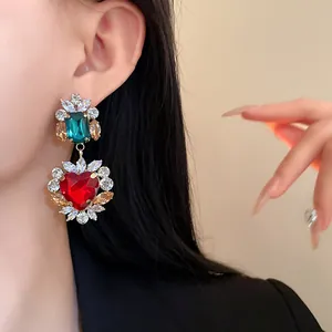 Primo piano dettagliato di orecchini pendenti vintage a forma di cuore con zirconi rossi e verdi