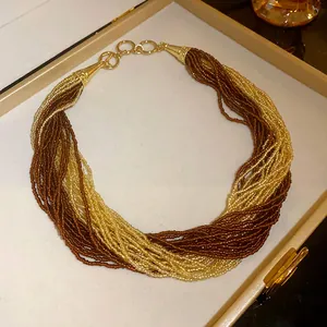 Detailed view of an elegant bohemian multi-layered seed bead necklace in brown and gold