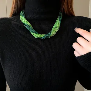Close-up of a Bohemian style multi-strand green seed bead necklace on a black turtleneck model