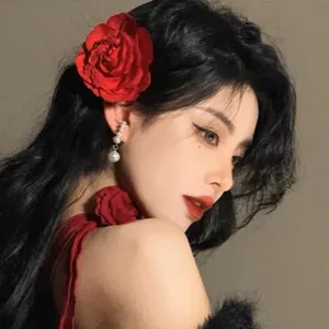 Elegant red fabric rose flower hair clip shown on model for a vintage aesthetic look.