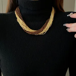 Detailed macro view of bohemian multilayer gold and brown seed bead necklace on model