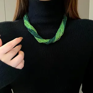 Detail showing multi-layer green seed bead necklace on a black turtleneck sweater