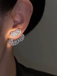 Detailed macro view of elegant silver-toned zircon butterfly earrings on a model's ear