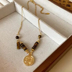 Detailed macro view of retro gold stainless steel necklace with brown tiger eye beads