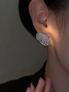 Close-up of elegant zircon butterfly stud earring worn on model's ear in warm light.