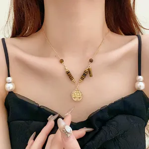 Close-up of a vintage gold necklace with tiger eye stone beads on a female model