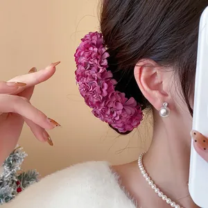 Macro detail of elegant deep purple fabric flower hairpin styled on a braided bun.