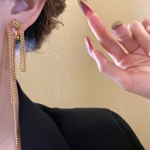 Close-up detail of 18k gold plated knotted tassel clip-on earrings on an Asian model