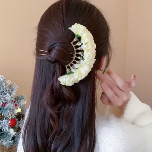 Detailed view of an elegant crescent fabric flower hair pin on a stylish bun hairstyle