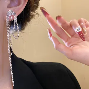 Detail shot of silver plated knotted tassel ear cuff on model with elegant manicure.