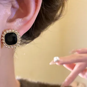 Vintage style black gemstone stud earrings with brilliant rhinestone halo on model's ear