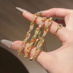 Détail de bracelets torsadés étincelants avec des zircons colorés tenus à la main
