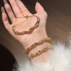 Vue détaillée d'un bracelet en or torsadé avec des zircons colorés sur un poignet féminin.