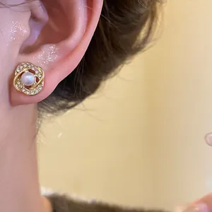 Detailed view of a gold-plated pearl earring with shimmering rhinestones in a vintage style.
