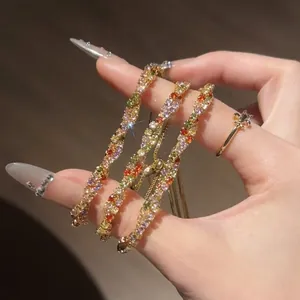 Gros plan de trois bracelets en zircon torsadés colorés avec fermoirs réglables à la main.