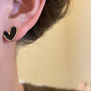 Detailed close-up of a French retro black heart stud earring with golden metal edge.