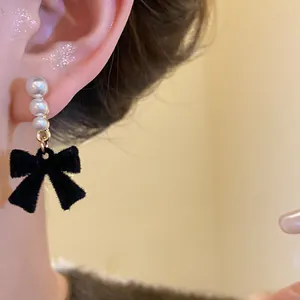 Close-up detail of a French vintage style earring with pearls and a black velvet bow