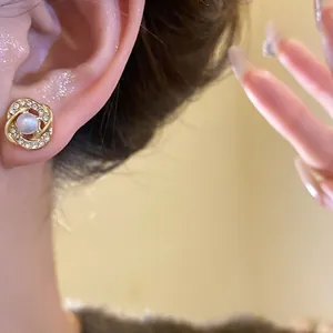 Close-up view of retro French style pearl gold stud earring with rhinestones on ear.