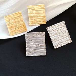 Detailed view of textured rectangular stud earrings in gold and silver finishes