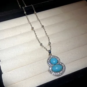 Elegant silver-toned gourd pendant necklace featuring blue stones and crystal accents