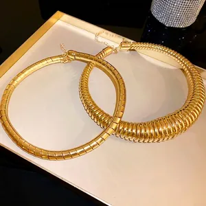 Chunky gold spring sliced choker necklace with adjustable chain on a tray