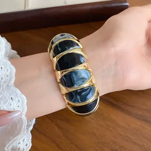 Detailed view of a French style marbled acrylic geometric elastic bracelet worn on a wrist