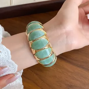 Macro view of a green marbled acrylic elastic bracelet with gold-tone metal framing.