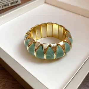 Close-up of French style marbled green acrylic geometric elastic bracelet with gold accents.
