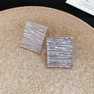 Detailed macro view showing the unique wrinkled texture of geometric silver stud earrings