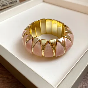 Close-up view of a pink marble acrylic and gold-tone geometric elastic stretch bracelet.