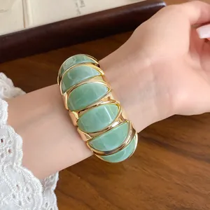 Detail view of a French marbled green acrylic elastic bracelet with gold metal spacers.