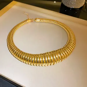 Close-up detail of oversized golden spring-style coiled necklace with high metallic luster