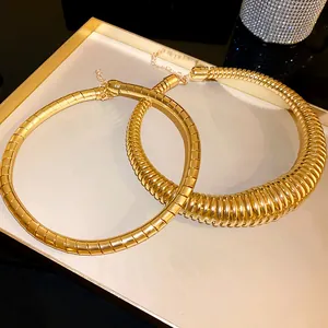Detail view of two chunky gold-toned spring segmented choker necklaces in a tray.