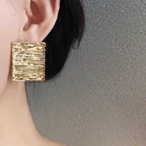 Detail view of gold geometric stud earrings with elegant wrinkled texture design for women.