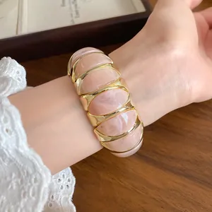 Close-up of a marbled pink acrylic and gold geometric elastic bracelet on a wrist