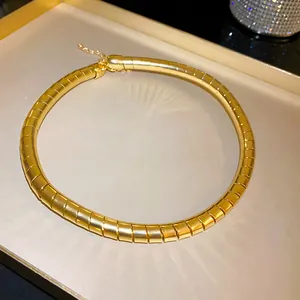 Macro view of a chunky gold segmented spring choker necklace with metallic high-polish finish