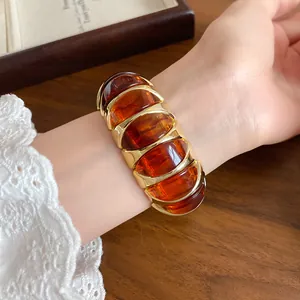 Close-up of French vintage amber acrylic and gold geometric elastic bracelet.