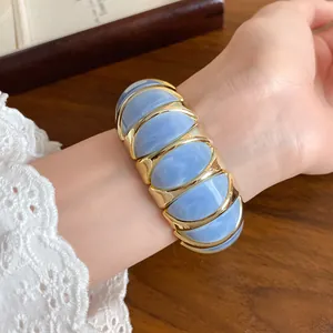 Close-up of French blue marbled acrylic and gold elastic bracelet on wrist.