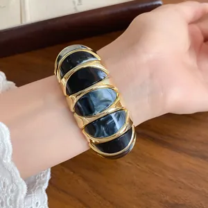Detail of French marbled acrylic geometric elastic bracelet on wrist, gold-tone finish