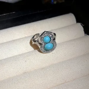 Close-up detail of a silver gourd-shaped ring featuring turquoise stones and crystals.
