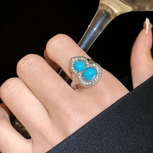 Close-up of a silver gourd ring with turquoise stones and shimmering diamonds