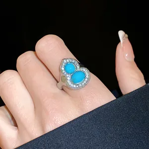 Close-up of a silver gourd-shaped ring featuring blue turquoise stones and diamonds