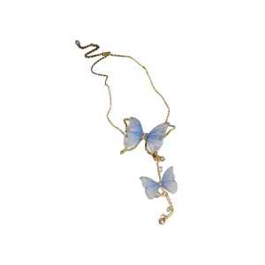 Elegante collana con farfalle in tulle blu, perle e cristalli su catena dorata.
